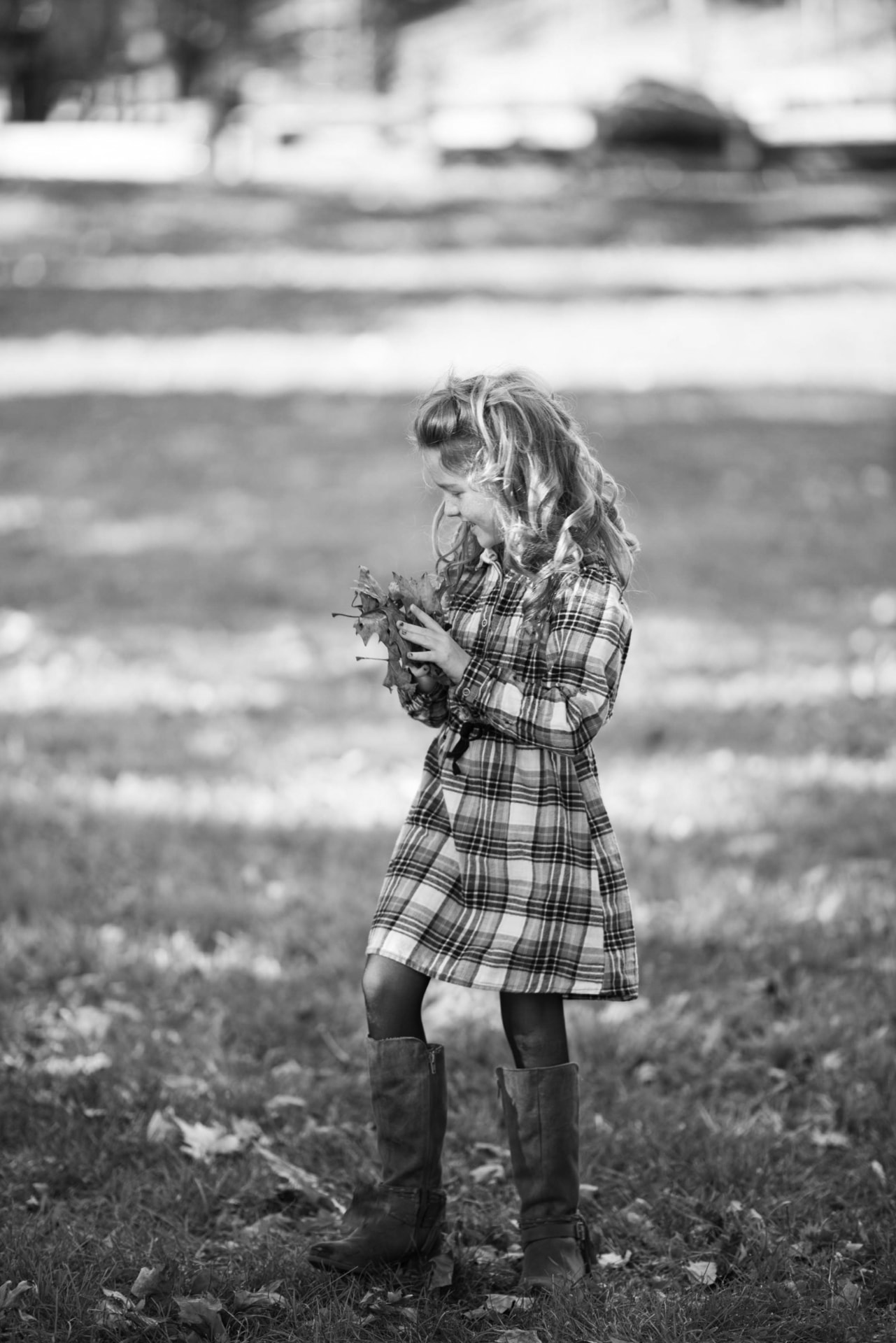 Girl in a plaid dress gathering fallen oak leaves